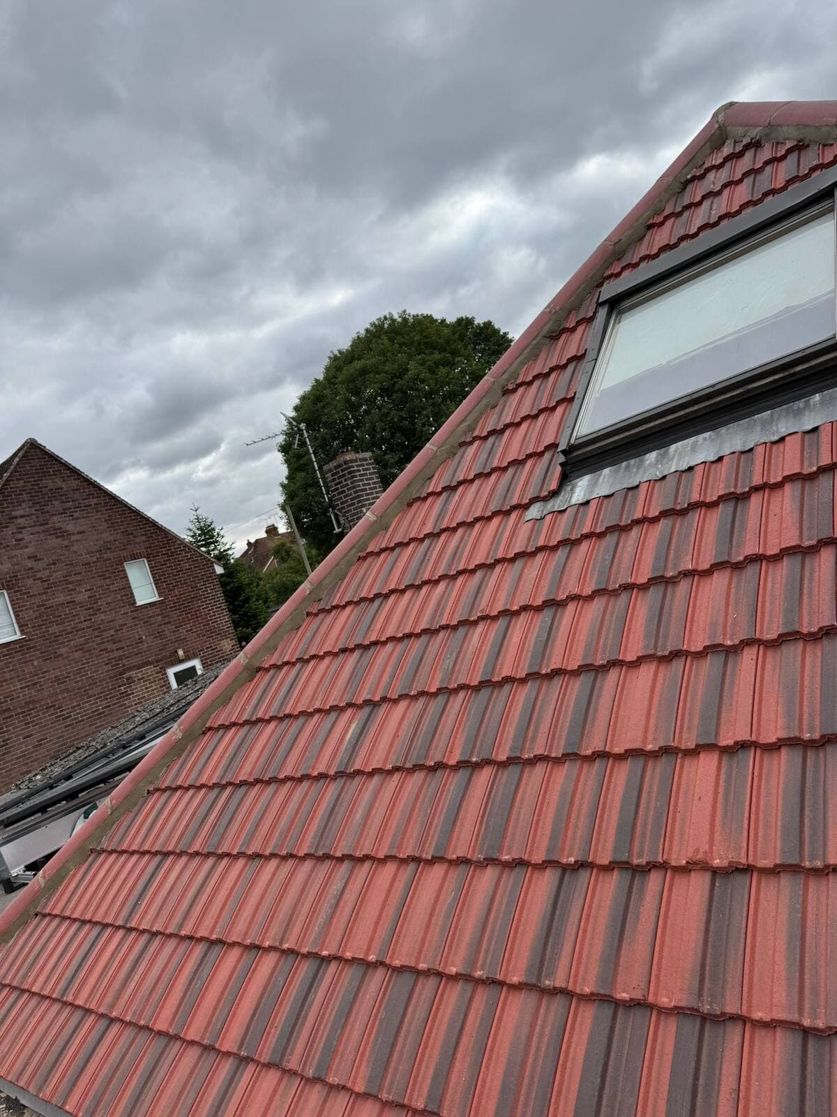 Completed red tile roof with Velux rooflight after re-roofing, Guildford area