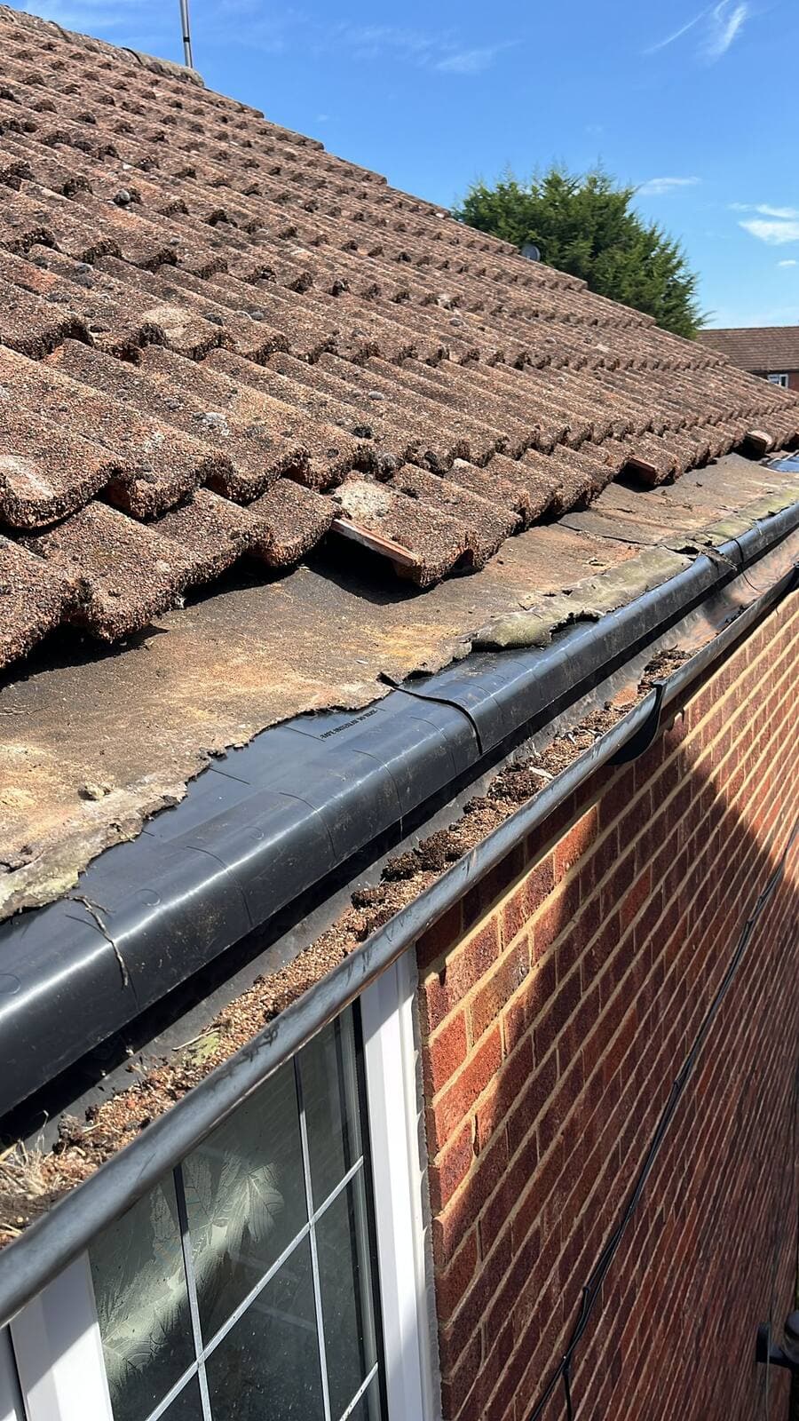 Worn roof tiles and damaged guttering before repair, Surrey